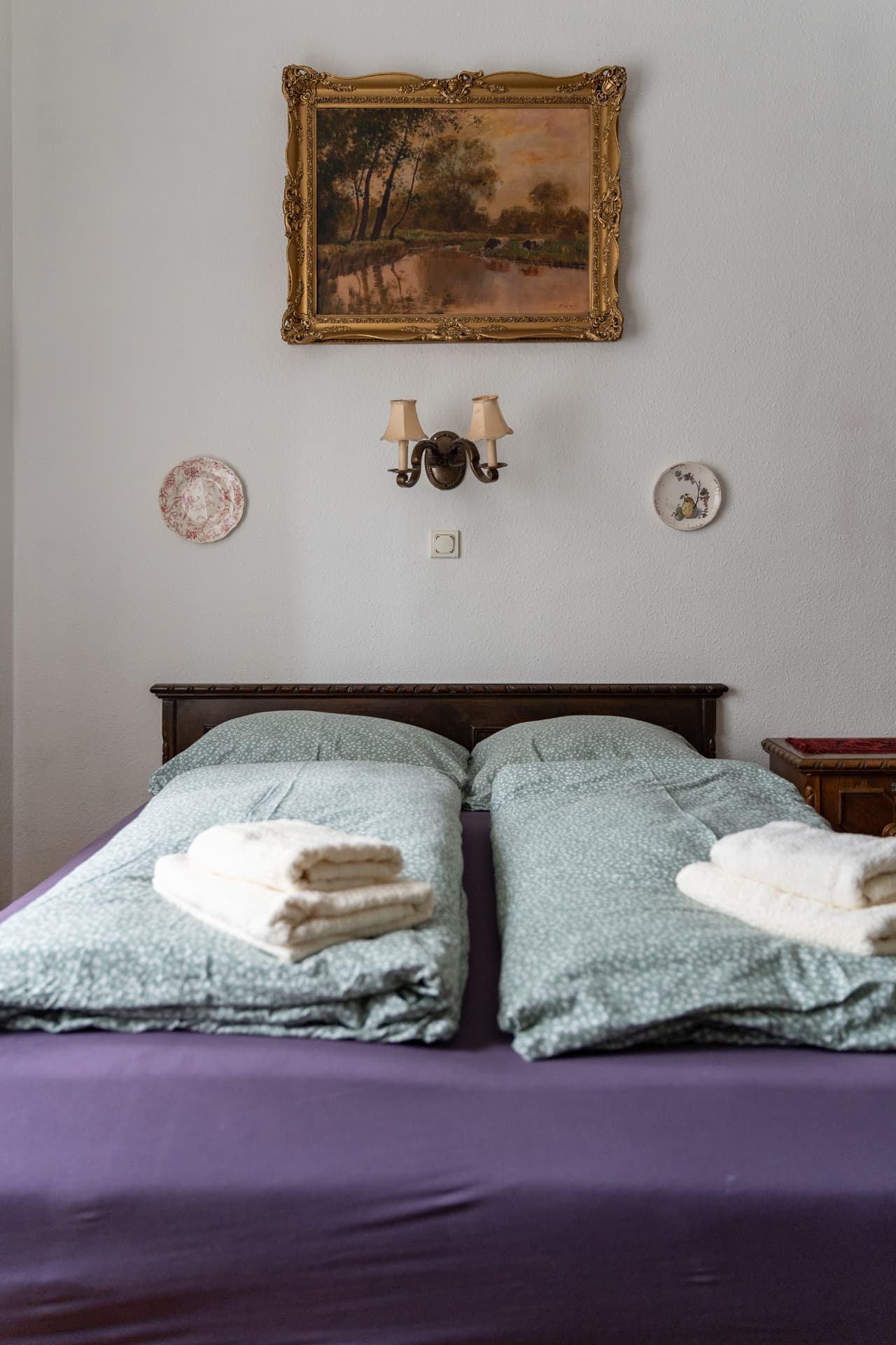 Bedroom detail with a painting and porcelain plates on the walls